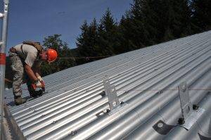 man on roof installing corrugated metal panels