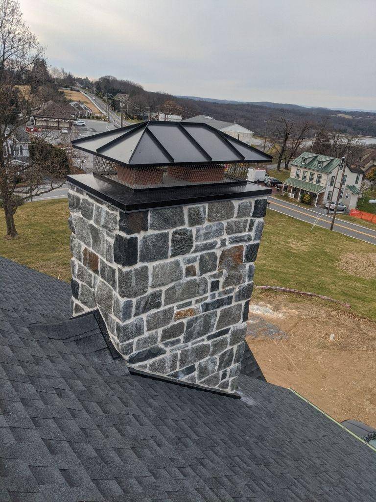 black metal, multi-flu chimney cap on stone chimney which Joyland Roofing installed 